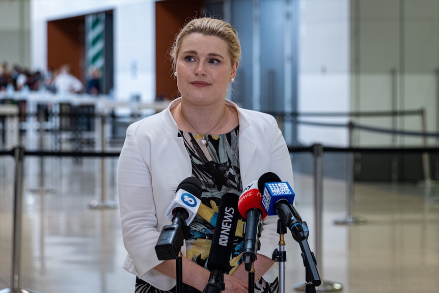 A woman standing in front of four microphones