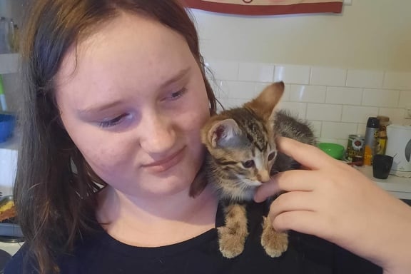 A teenager with a kitten on her shoulder