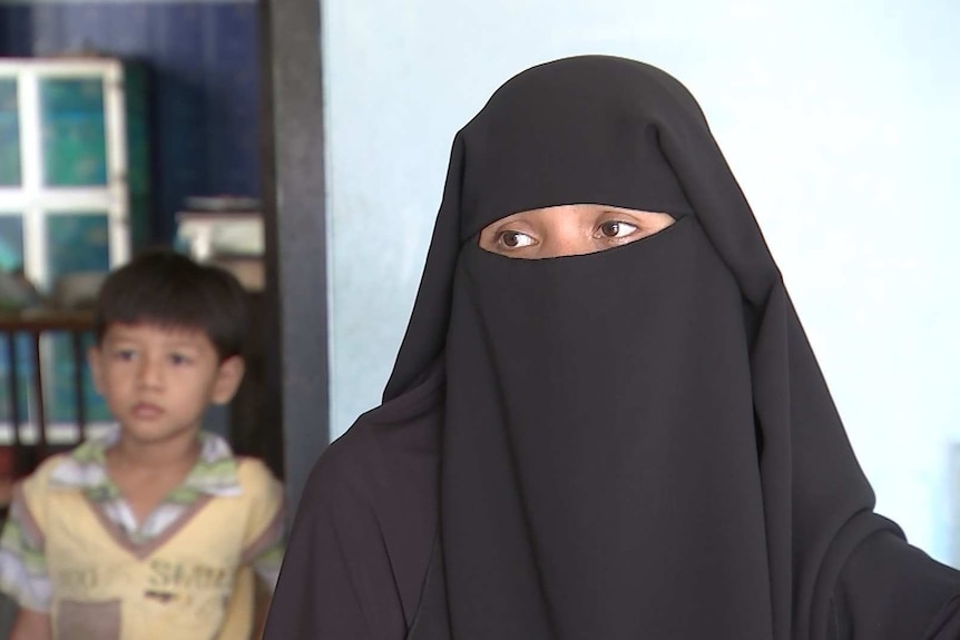 Accused Indonesian terrorist Adi Jihadi's wife Heni wearing face covering with child in background