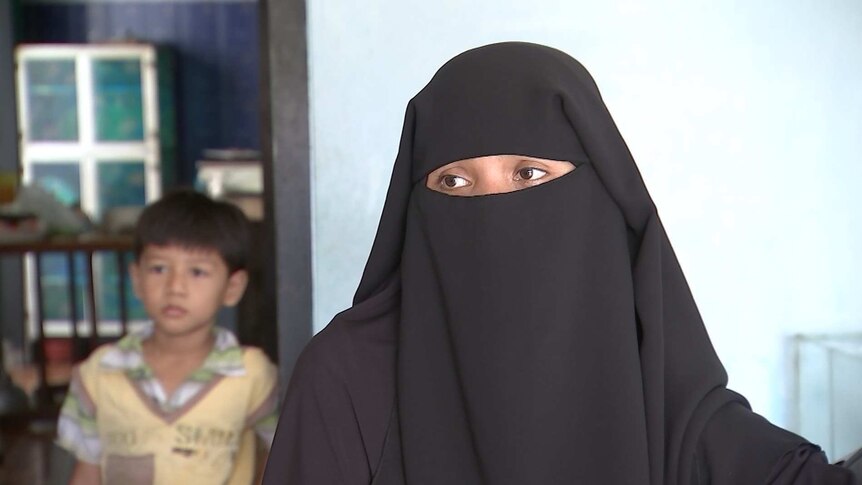 Accused Indonesian terrorist Adi Jihadi's wife Heni wearing face covering with child in background