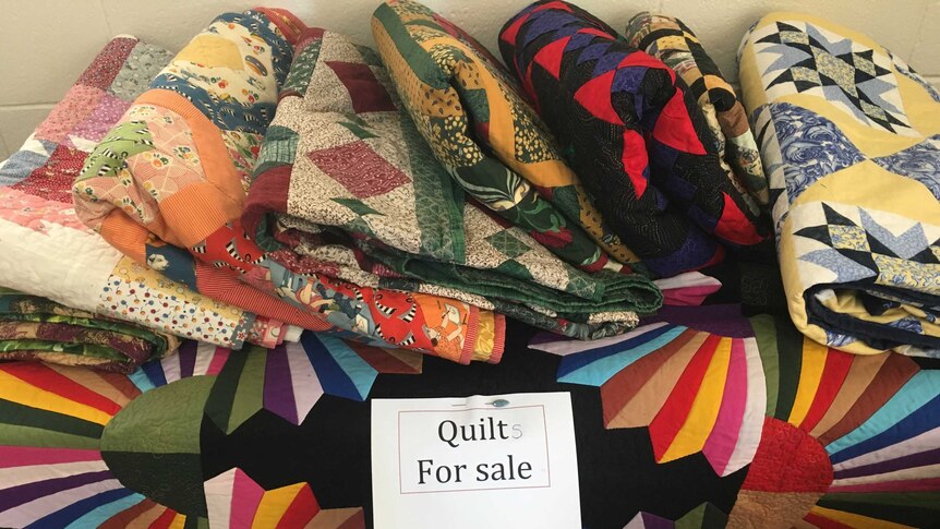 Colourful quilts folded up for sale