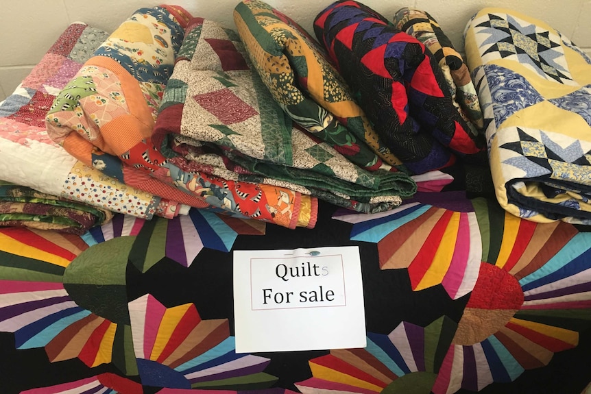 Colourful quilts folded up for sale