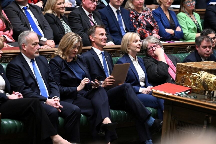 liz truss on the benches of parliament with jeremy hunt, who is smiling, penny maudent looking at her phone