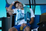 Novak Djokovic tilts and touches his head at a change of ends.