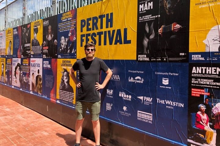 a man in front of signs for perth festival