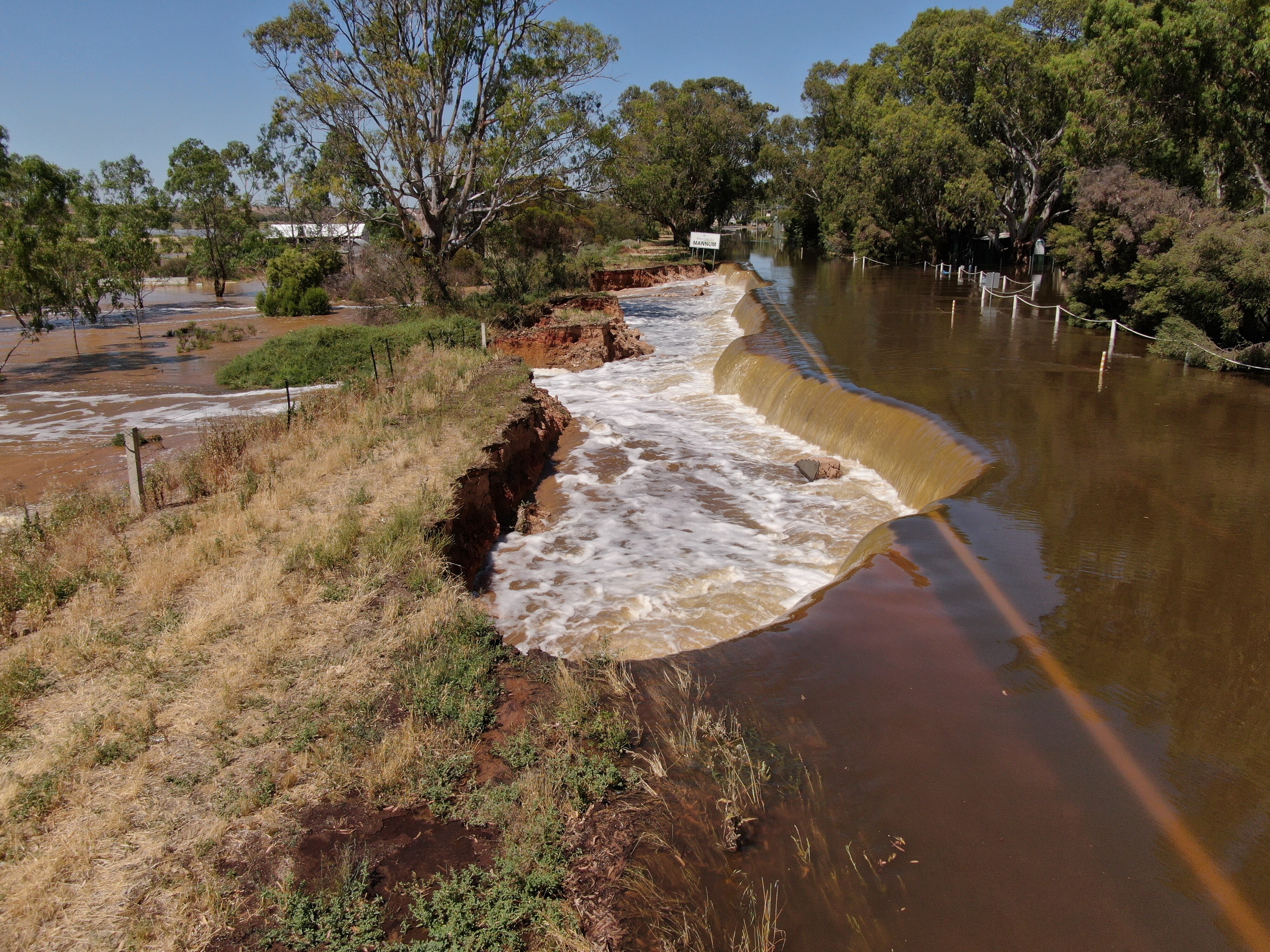Part of a road collapsed with water gushing through farmlands