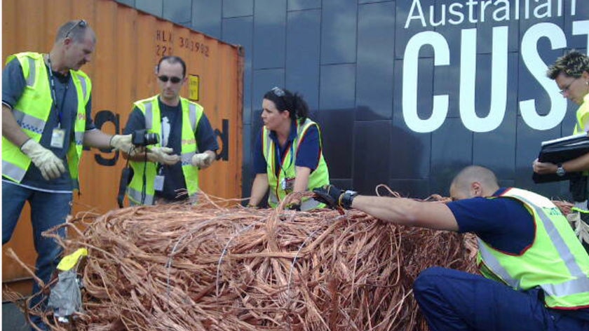 Customs officials examine a bale of stolen copper hidden in a shipping container in Melbourne.