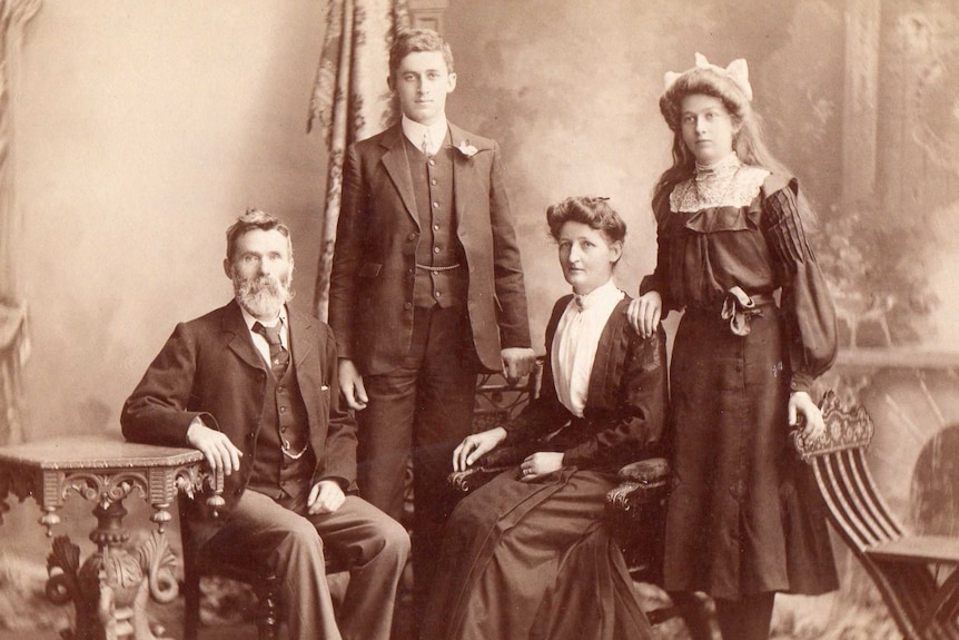 An old sepia filtered photo of a father, mother, brother and sister taken in the early 1900's.