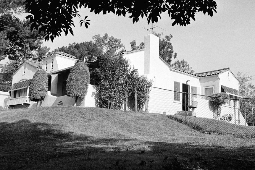 A black and white photo  of a rich-looking home on a hill.