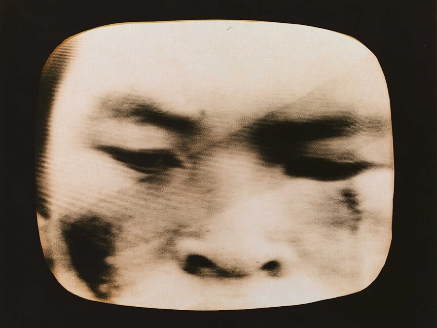An extreme close up of a man's face on a black and white television set