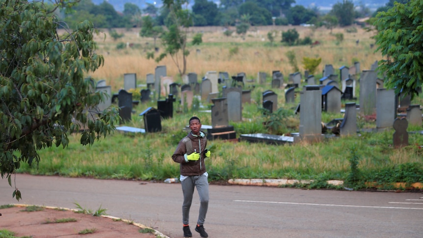 a person jogging a long a street next to a cemetery