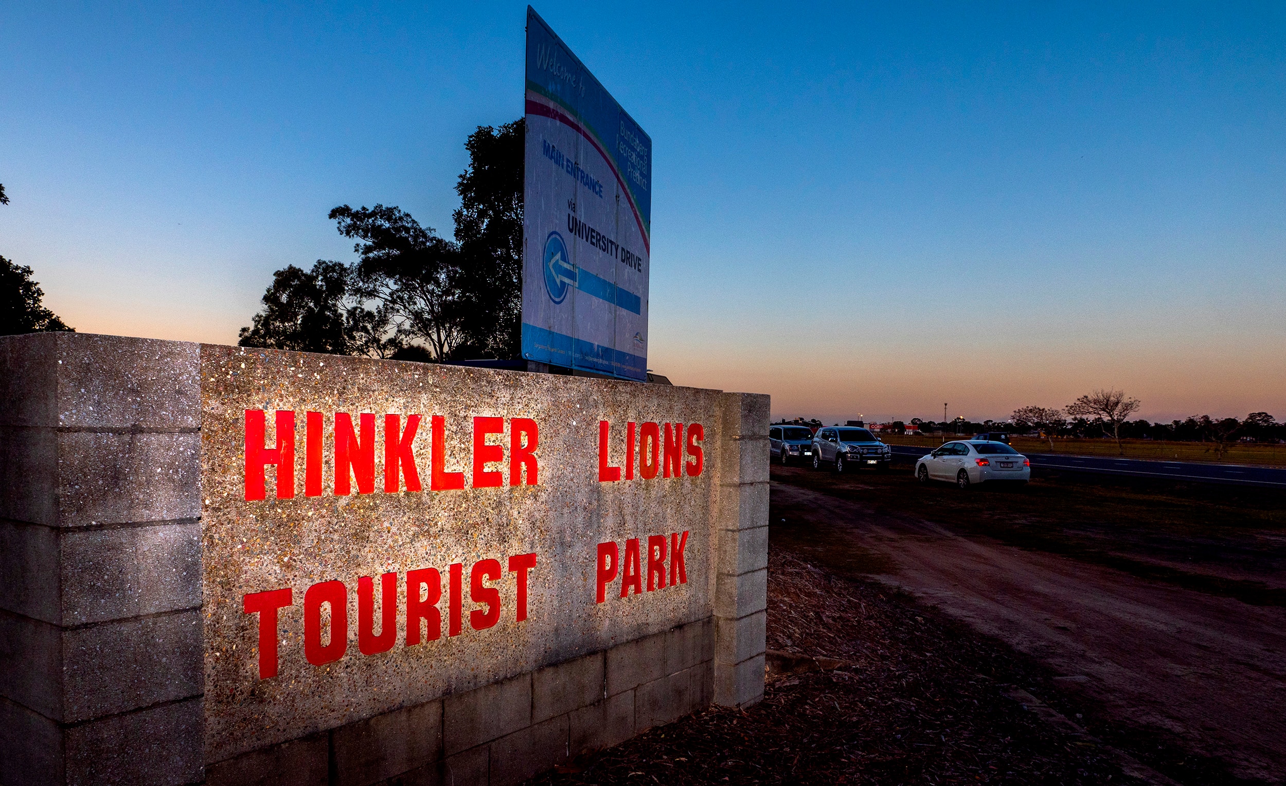 A sign at sunset with the words Hinkler Lions Tourist Park.
