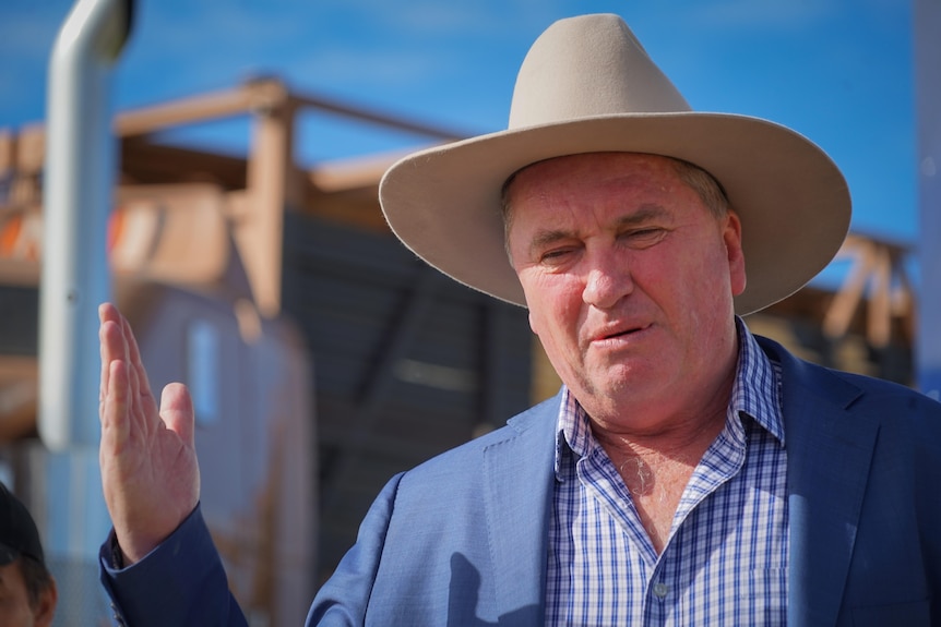 Deputy PM Barnaby Joyce speaking with his hand raised in an outback location.