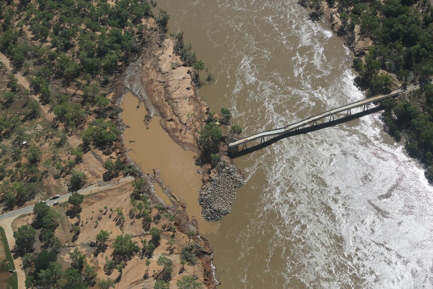 An aerial shot of a damaged bridge over a river