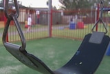 A swing in a park with children in the background