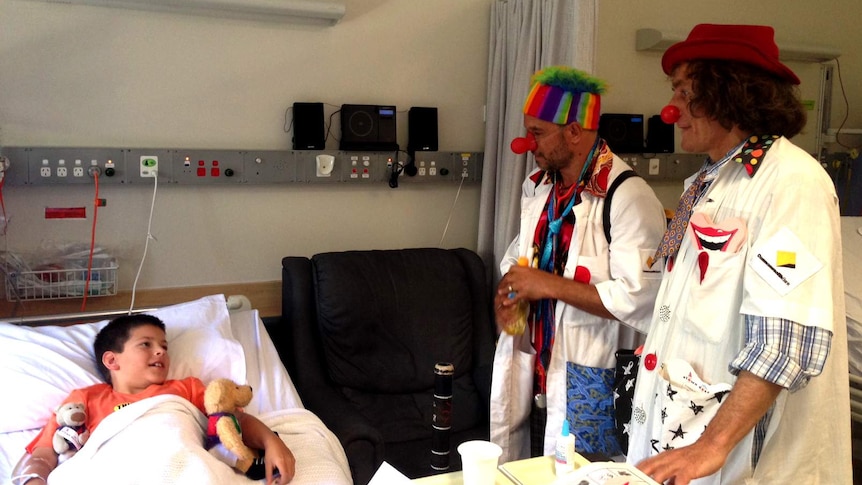 A patient at PMH checks out two clown doctors by his bed