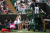 A tennis player with hands on hips argues with a chair umpire at Wimbledon.