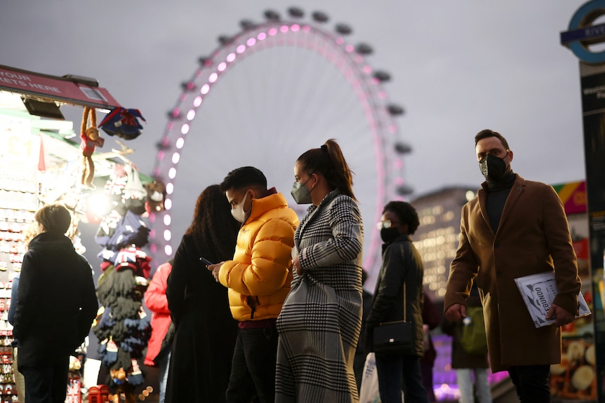 Oamenii trec peste podul Westminster, trecând pe lângă un magazin cu lumini puternice