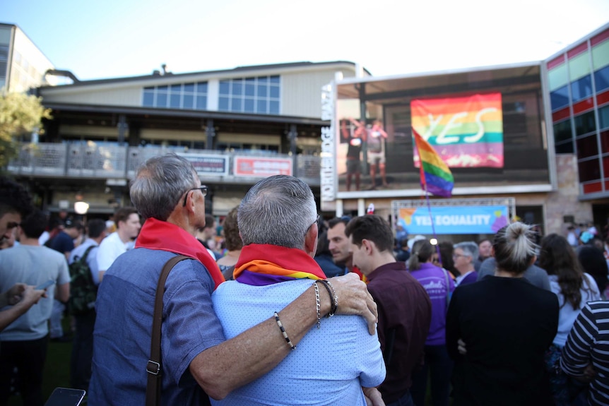 Mandurah couple Neil Connery and Geoff Bishop stand in a large crowd at Northbridge Piazza satching a big screen.