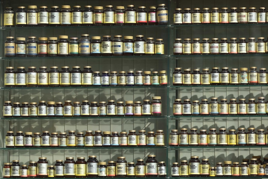 A pharmacy shelf lined with jars of various health supplements.
