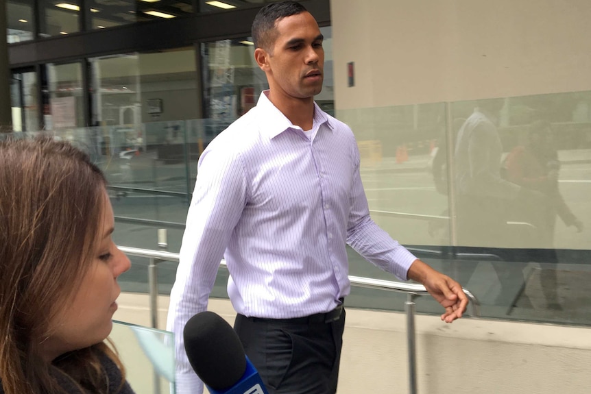 Shane Yarran walks along the street as a channel 9 reporter follows alongside trying to ask a question.
