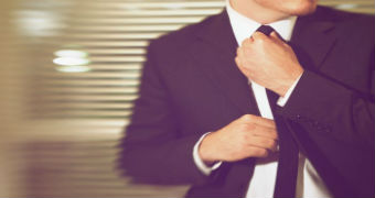 A man in a suit fixes his tie
