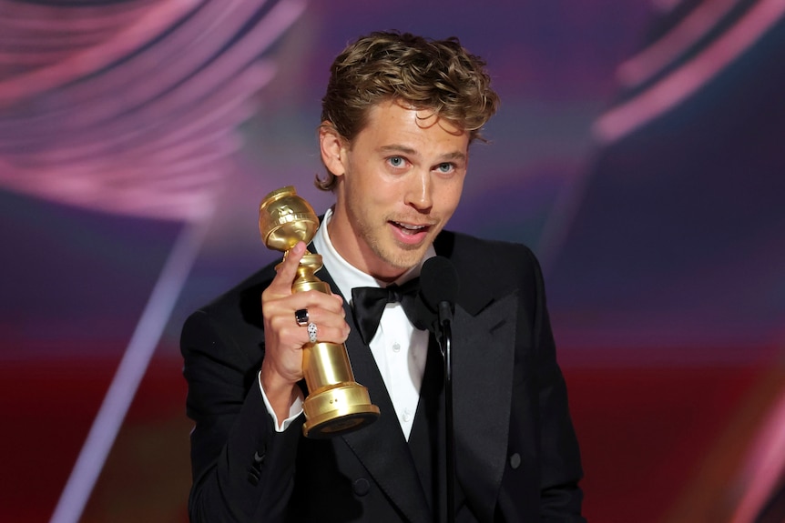 An actor on stage holding a Golden Globe award