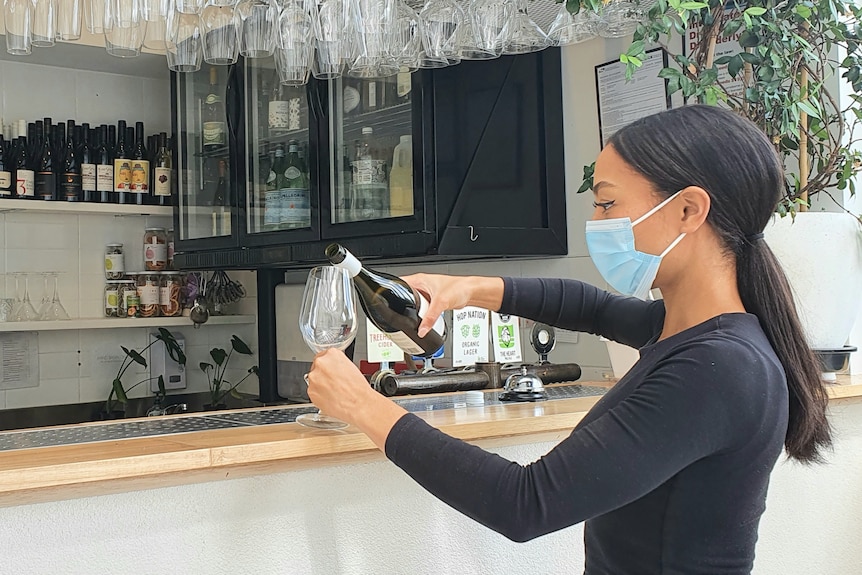 Havana Tan pours a glass of wine at the bar in her restaurant