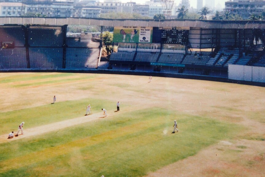 A picture from high in the stands of cricketers playing on a browning turf.