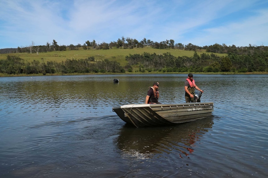 two fishermen in a small dinghy on a dam