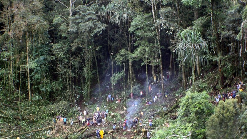 Rescue workers and nearby villagers clear the site where an Airlines PNG Twin Otter aircraft crashed