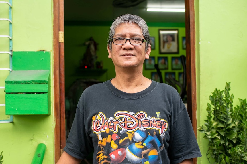 A man in a Walt Disney shirt smiles outside a lime green building