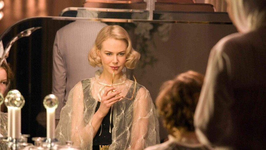 Nicole Kidman stares pensively with the frame of her glasses resting on her lip
