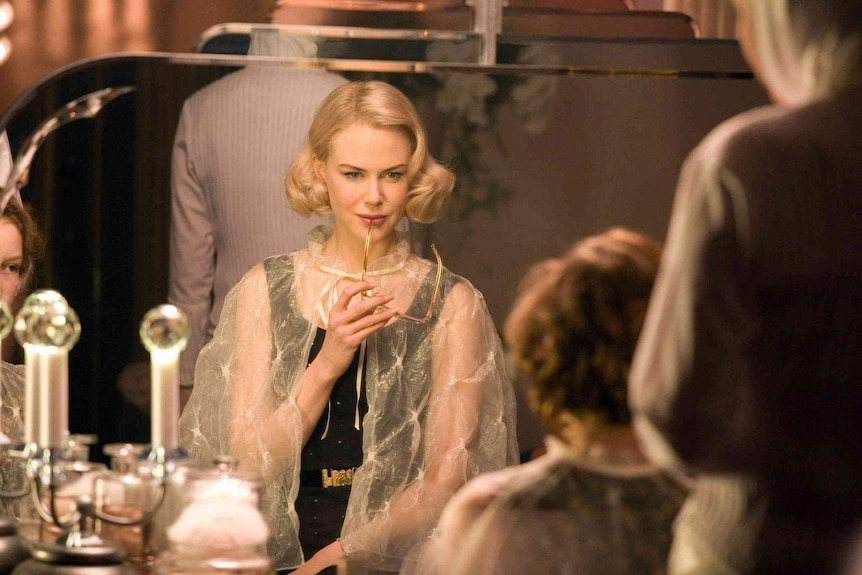 Nicole Kidman stares pensively with the frame of her glasses resting on her lip