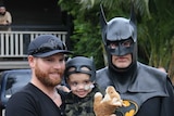 Jeff Vale holding son Eli Vale standing next to Craig Blackburn, dressed as Batman
