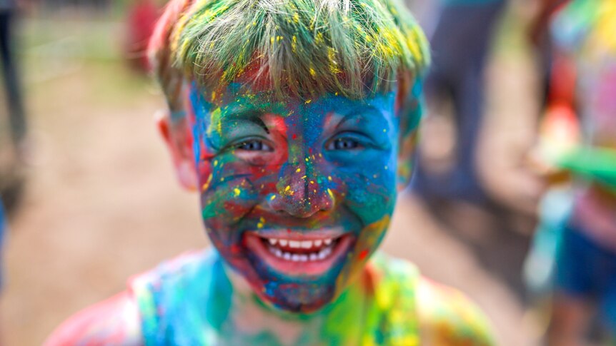 A little boy covered in coloured powder