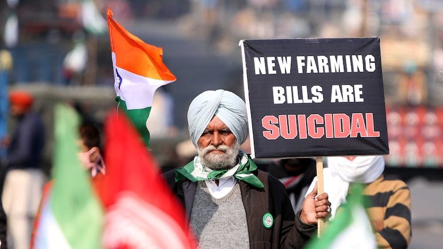 A Sikh protester holds up a sign condemning the Indian Government's proposed agriculture laws