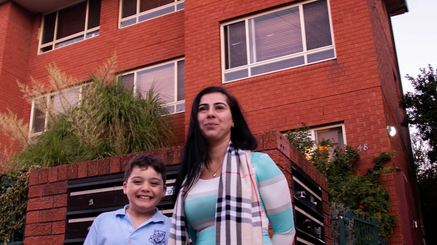 Rima Israel and her son stand outside an apartment block