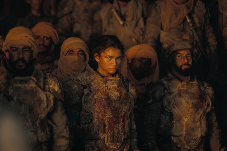 A film still of Zendaya in a crowd. She looks battered and angry.