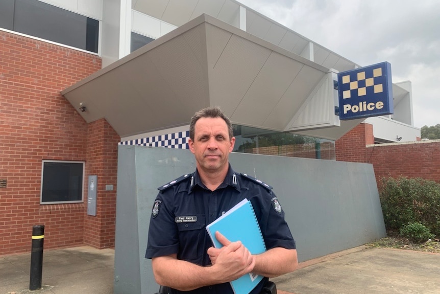 policeman in uniform poses outside station 