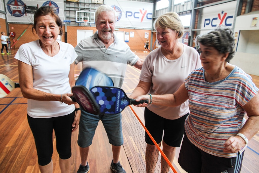 Four pickleball players congratulate each other on having had a good game.