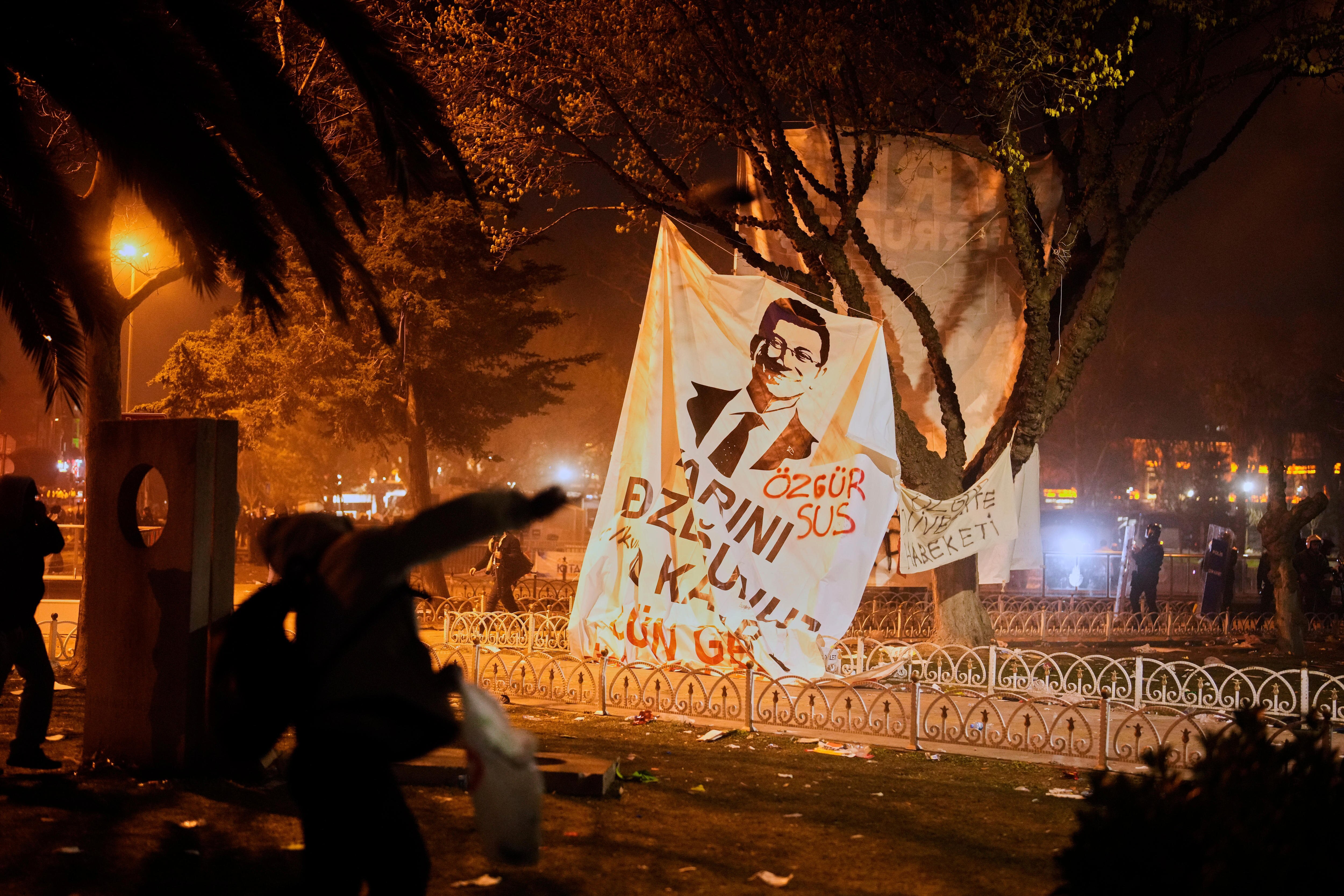 Protesters at night with a sheet hanging from the trees with  Istanbul's Mayor Ekrem Imamoglu  face on it