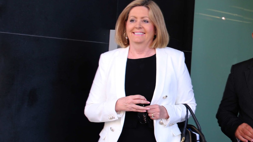 A smiling Perth Lord Mayor Lisa Scaffidi walks out of the State Administrative Tribunal wearing a white jacket and black top.