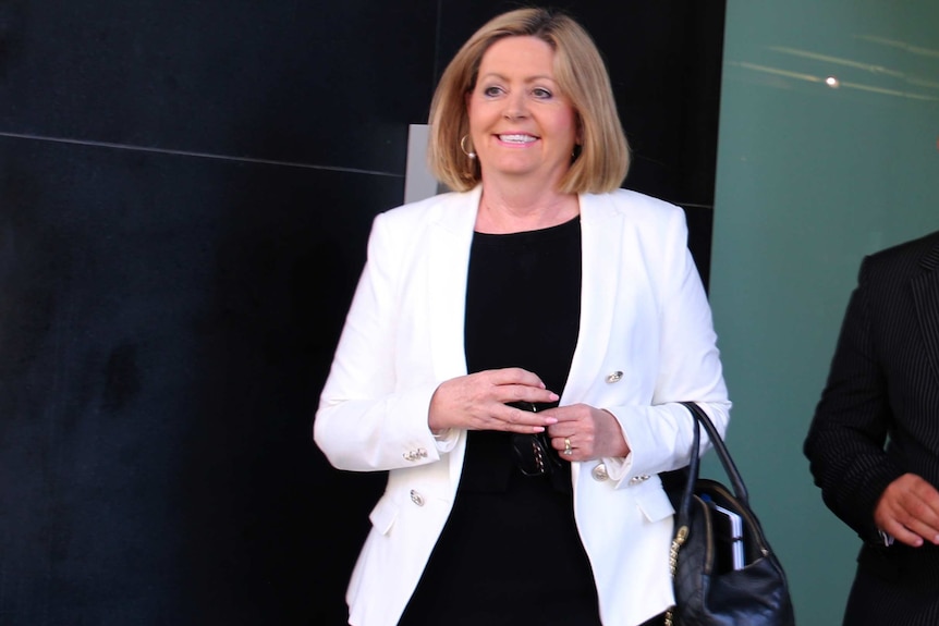 A smiling Perth Lord Mayor Lisa Scaffidi walks out of the State Administrative Tribunal wearing a white jacket and black top.