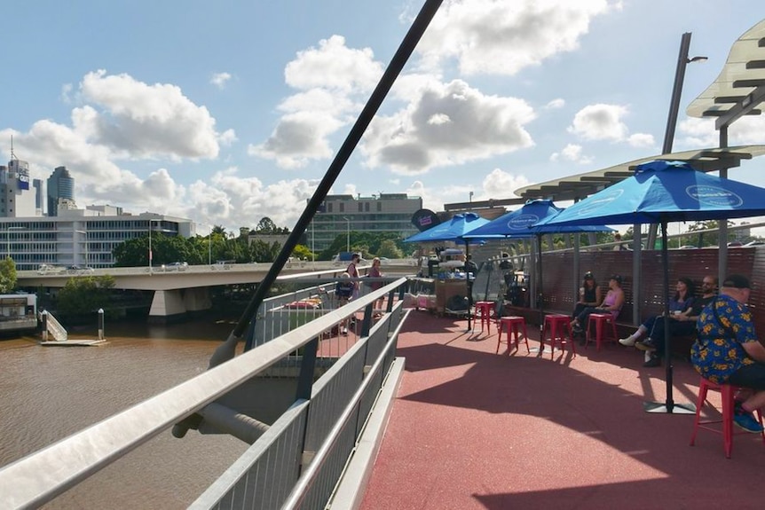 People sitting under large umbrellas overlooking a river