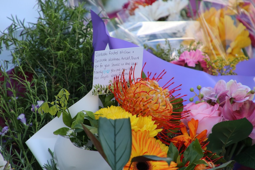 A card among flowers to Queensland police victims describes them as "blue angels".