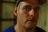 Matthew Norman wears a baseball hat and stares directly at the camera