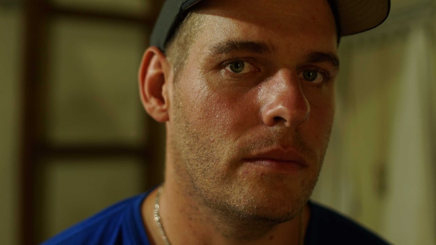 Matthew Norman wears a baseball hat and stares directly at the camera