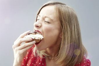 A woman eating a cream bun.