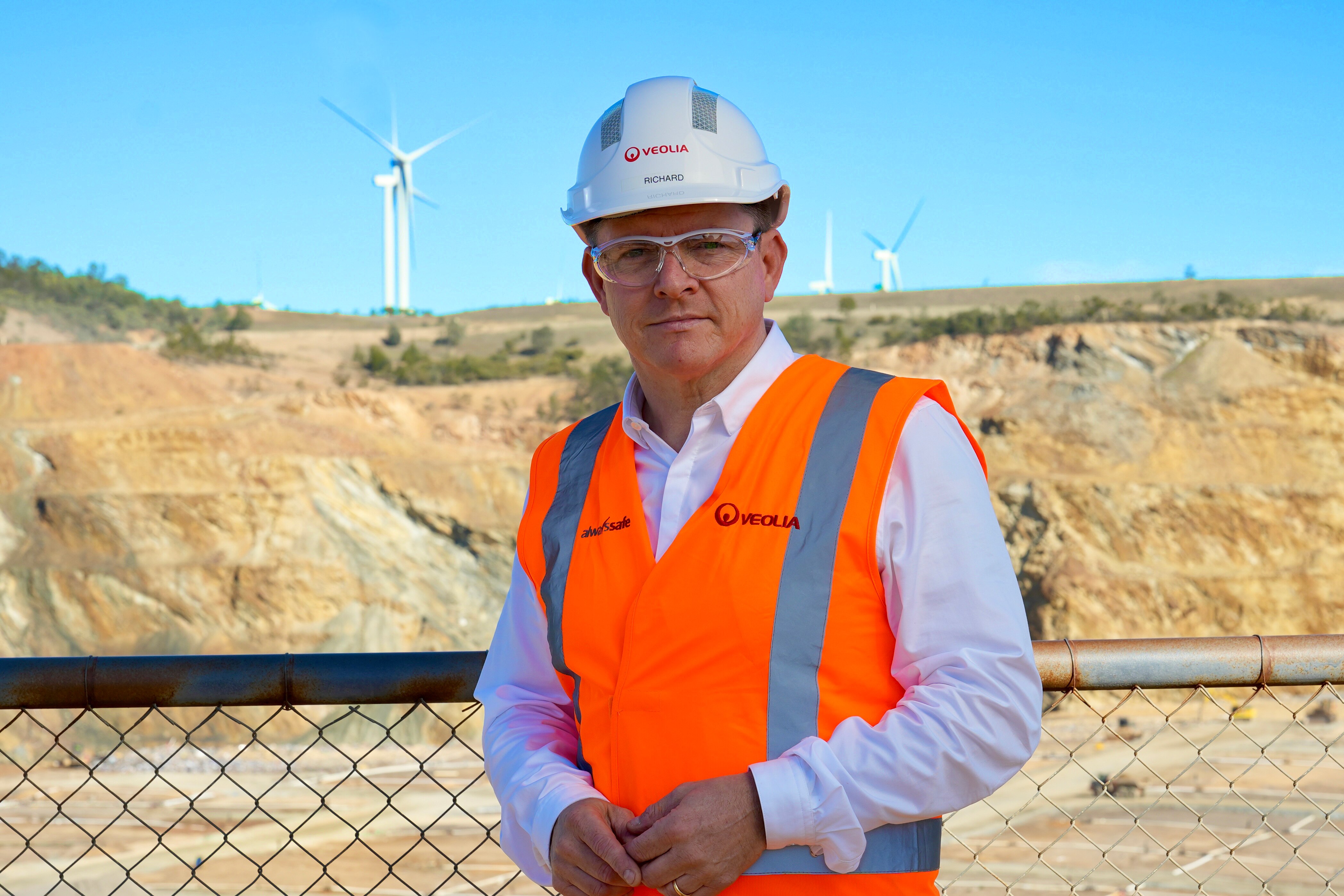 Hombre con una camiseta de negocios, chaleco de alta visibilidad y un sombrero duro.